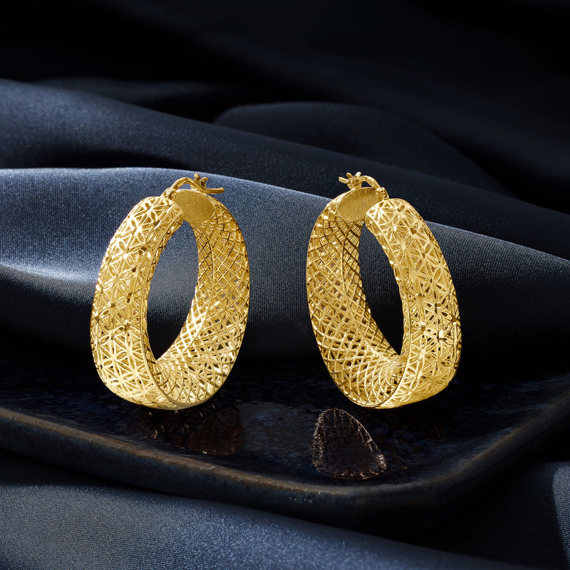 Gold openwork oval hoop earrings shown on fabric, pair view.