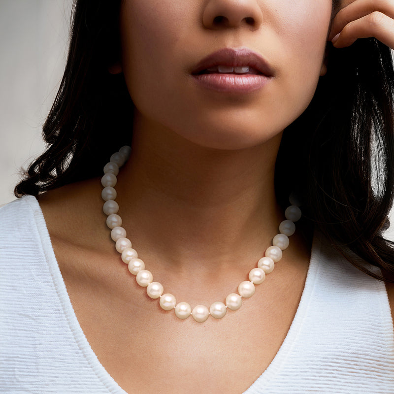 Cultured pearl necklace on model, round white pearls in a single strand.