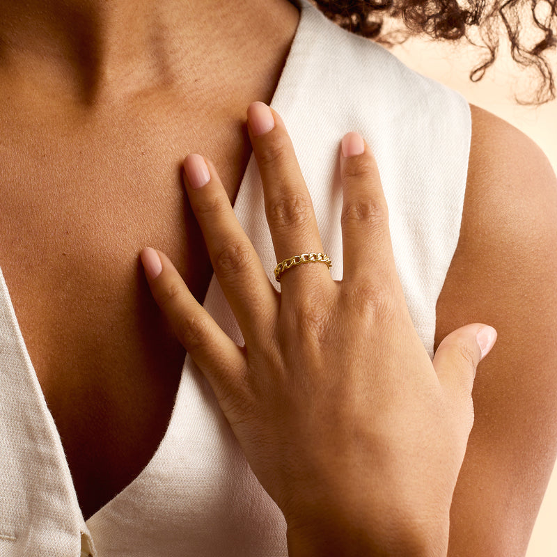 Yellow gold curb-link ring on finger, polished oval links.