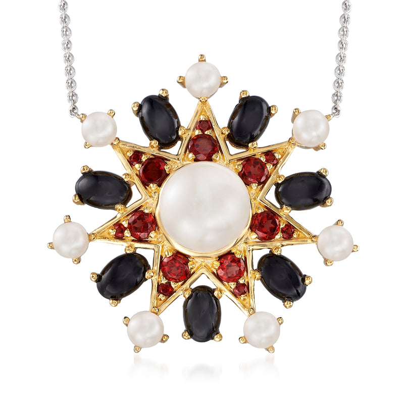 Gold-tone pendant necklace with central cultured pearl, red gems, and black oval stones