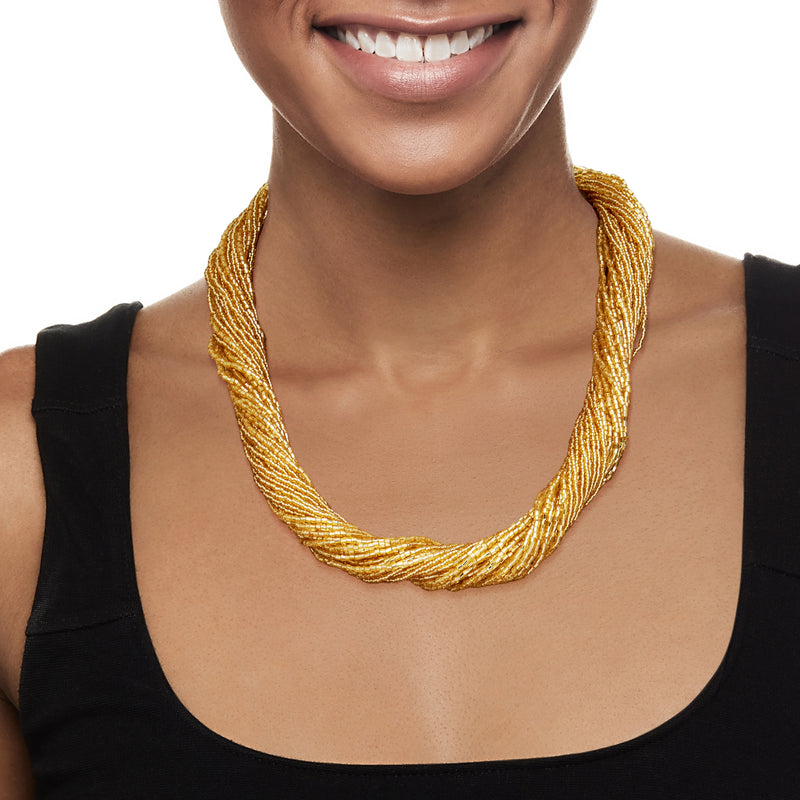 Golden bead torsade necklace worn with black sleeveless top, layered twisted strands