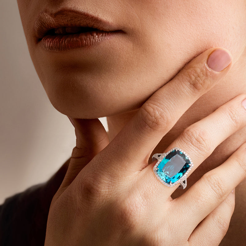 London blue topaz and diamond ring on hand, cushion-cut blue center stone, white gold band