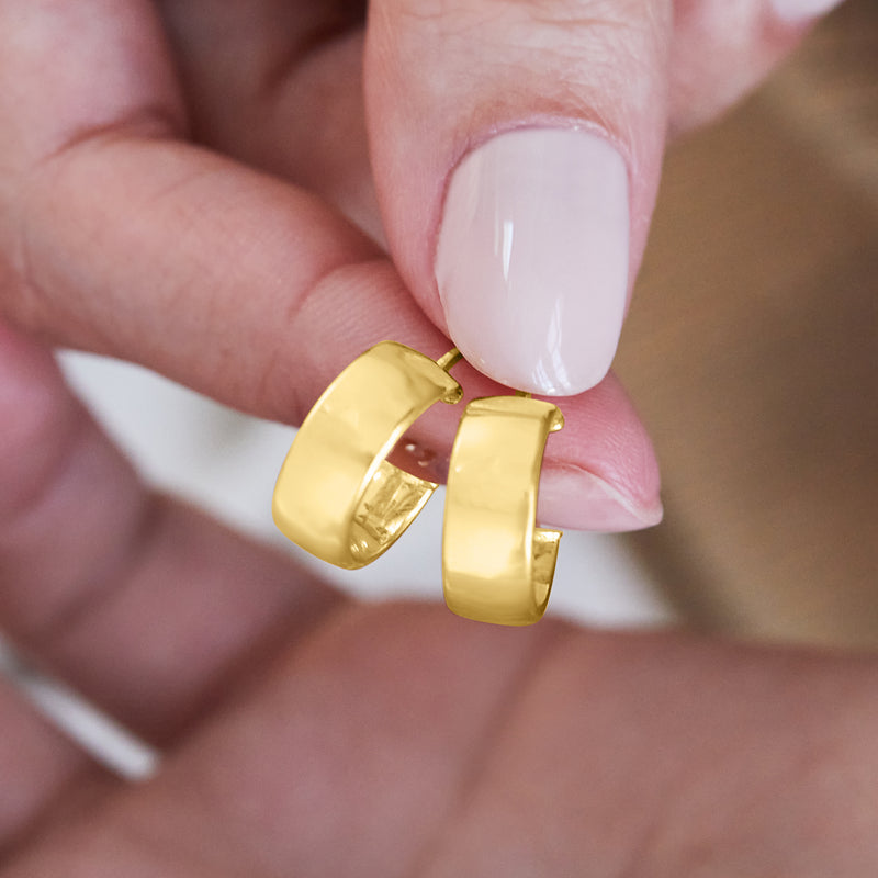 Hinged yellow gold huggie hoop earring close-up, glossy clasp