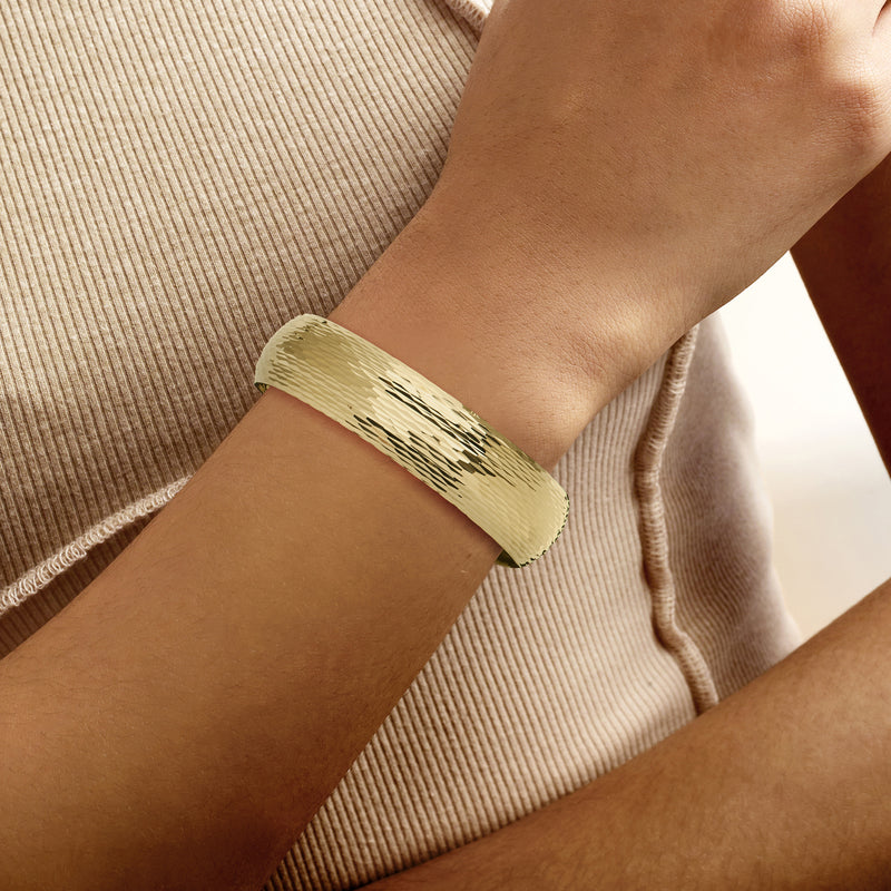 14kt yellow gold bangle bracelet worn on wrist, hammered ridged band