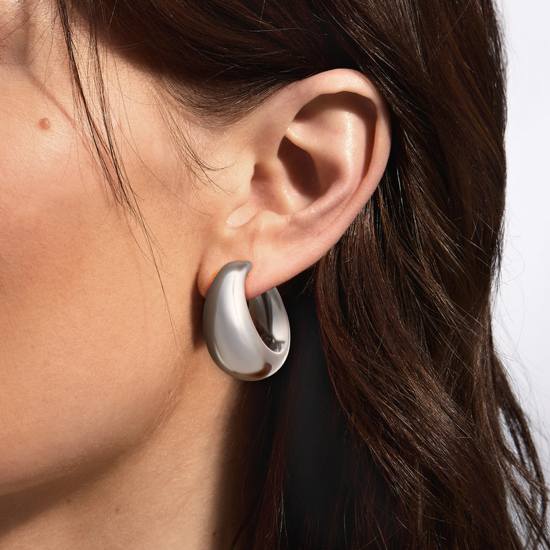 Sterling silver graduated hoop earrings on ear, smooth curved oval hoops