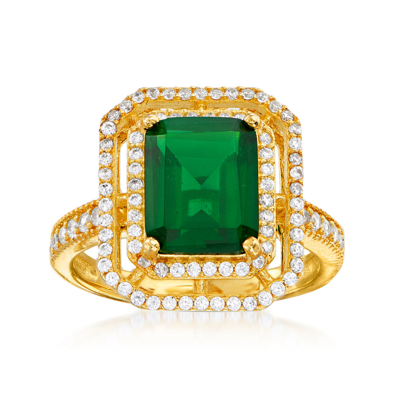 Gold-tone ring with square green simulated emerald center and CZ halo rows, cushion frame