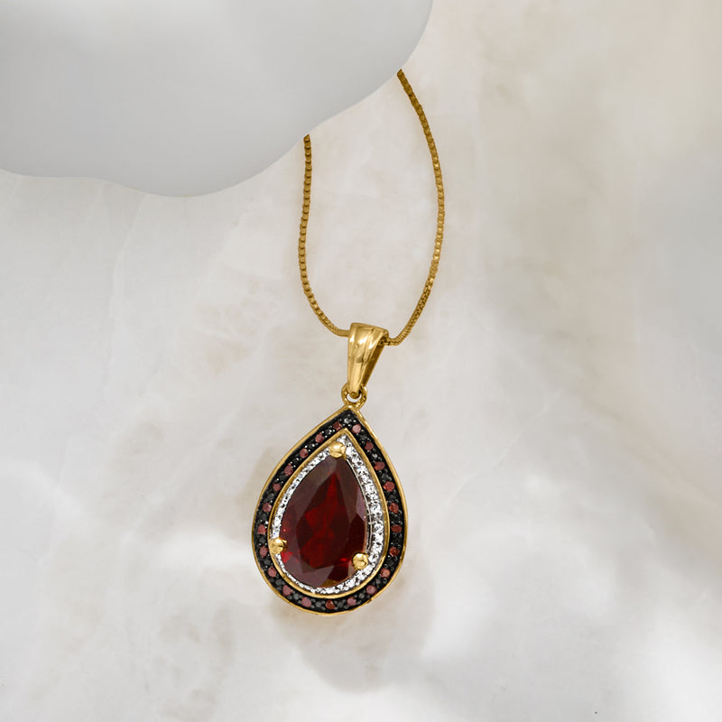 Gold teardrop garnet pendant necklace with red center stone and diamond border