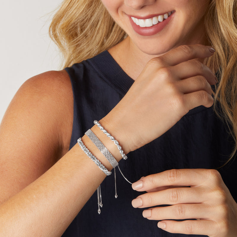 Sterling silver bolo bracelets on wrist with wide mesh cuff and slim chain bangles