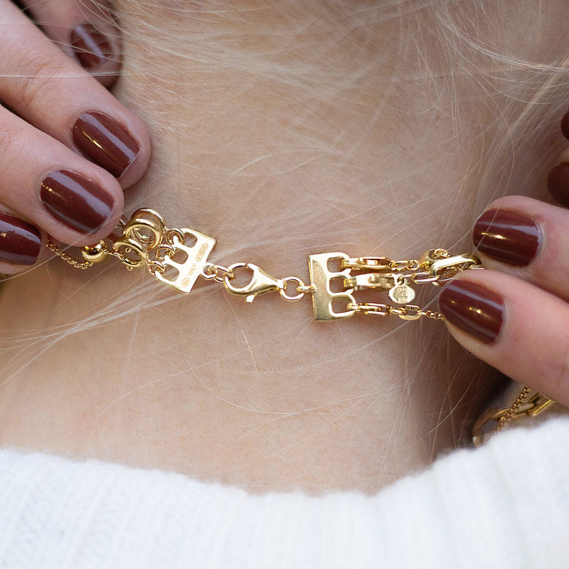 Gold clasp and link chain bracelet on wrist, hands holding layering segment