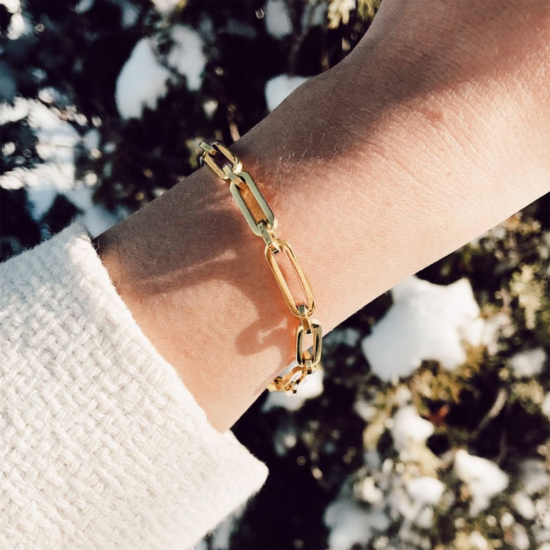 Yellow gold paper clip link bracelet close-up on wrist, hinged oval links