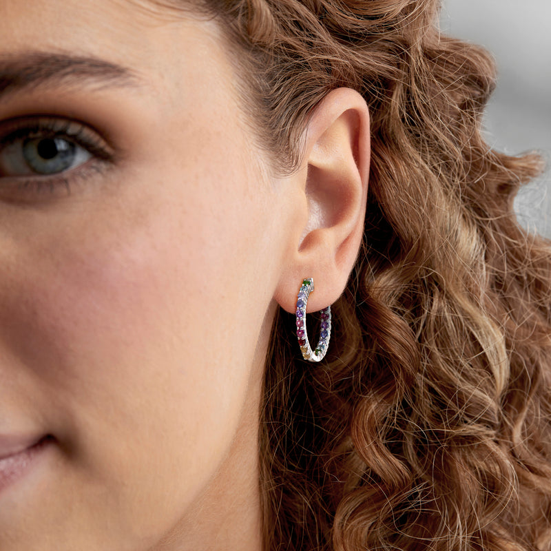 Sterling silver hoop earrings with rainbow gemstone accents on ear close-up