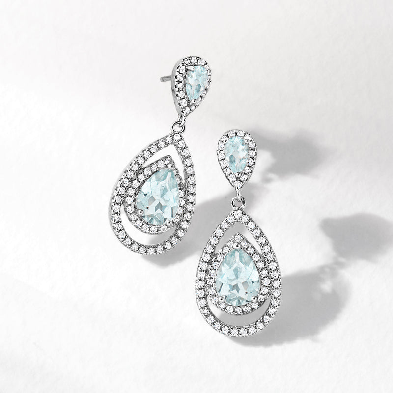 Sterling silver drop earrings with blue aquamarine teardrop centers and white topaz halo