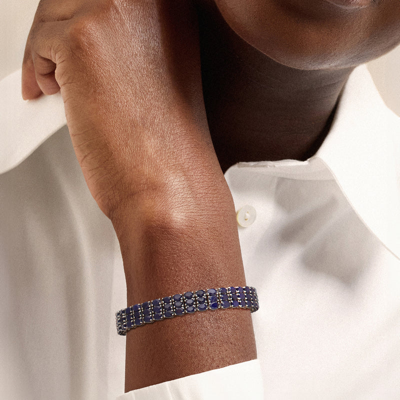 Sapphire tennis bracelet on wrist with blue gemstone row design in sterling silver