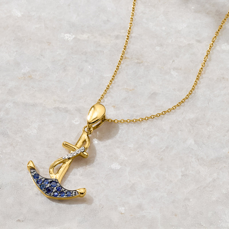 Gold-tone anchor pendant necklace with blue sapphire stones and clear top accents
