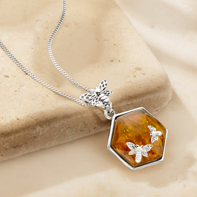 Sterling silver pendant necklace with amber octagon resin and bee motifs, close-up