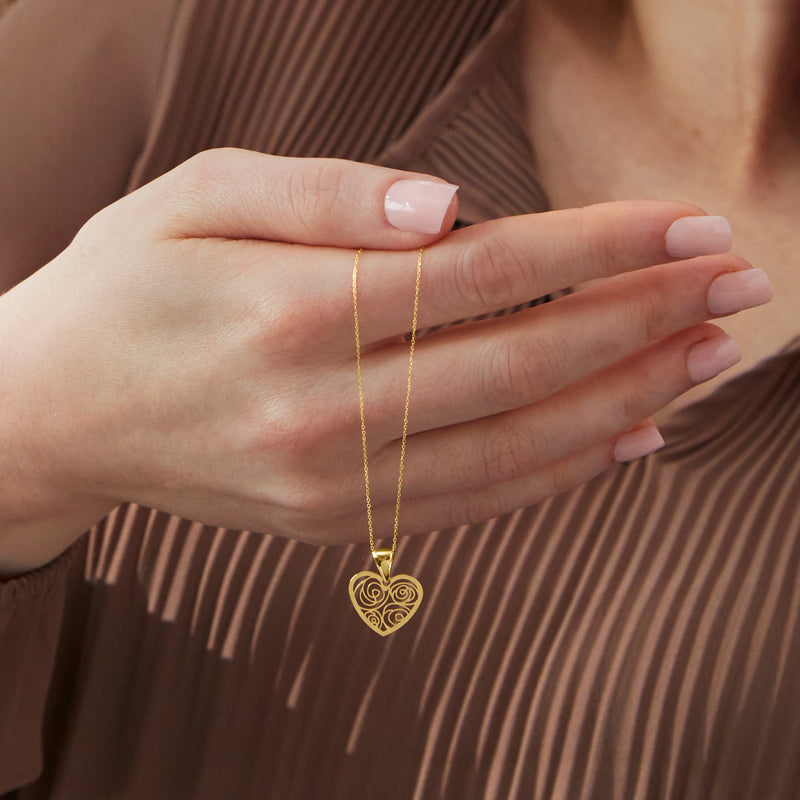 Yellow gold openwork heart pendant necklace worn on hand, fine chain