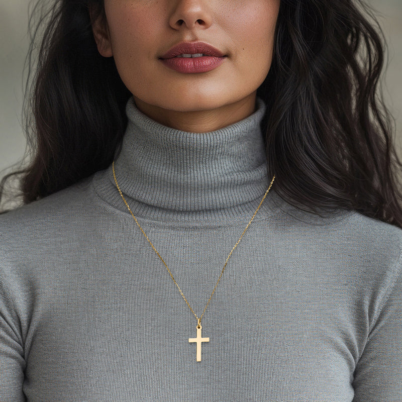 Yellow gold cross pendant on a fine chain, worn at the neckline