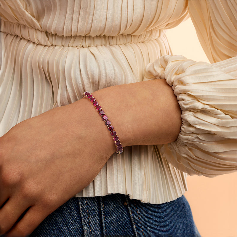 Rhodolite garnet tennis bracelet on wrist with oval pink-red stones in rose gold