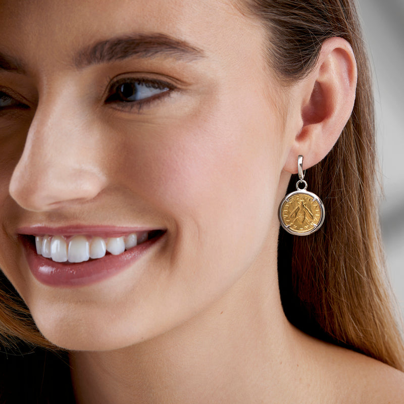 Coin drop earrings with round gold-tone bee coin medallion on silver hoop, worn