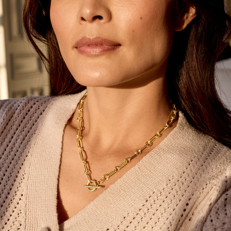 Gold paper clip link necklace worn close to collar with toggle clasp