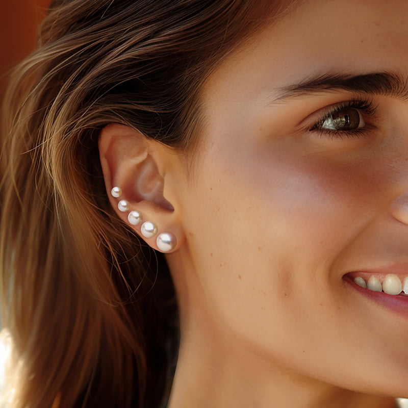 Cultured pearl stud earrings on ear: multiple 4–8mm pearls on silver posts
