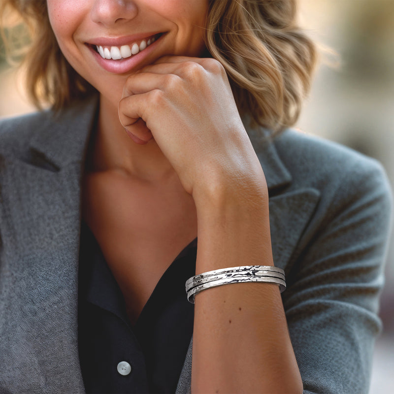 Stacked hammered sterling silver bangle bracelets on wrist, wide cuff style