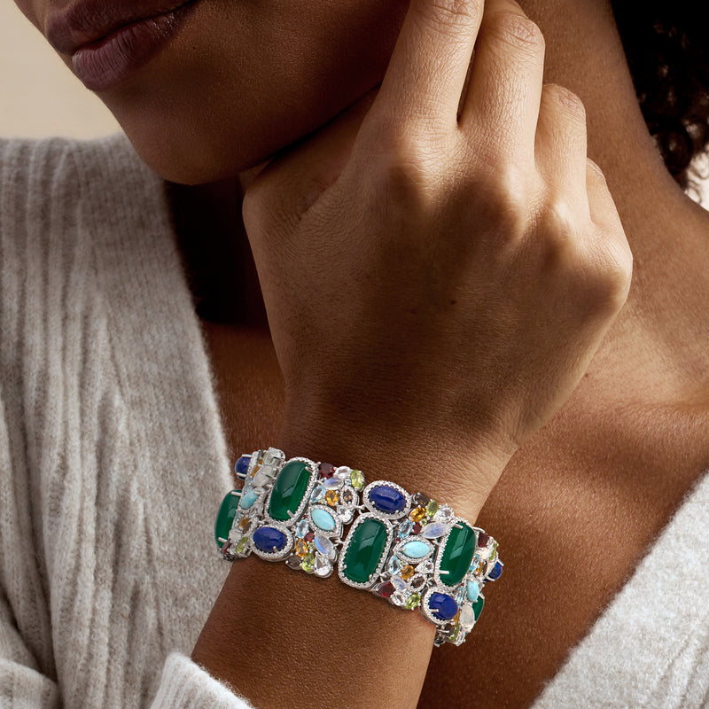 Sterling silver multi-gem bracelet worn on wrist with green, blue, and crystal-clear stones