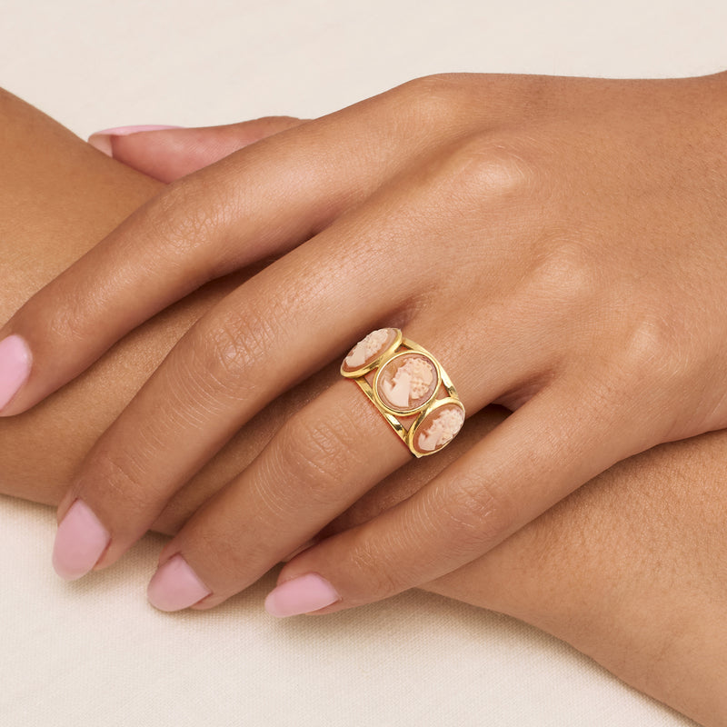Gold-tone cameo ring on hand with three oval shell cameos on openwork band