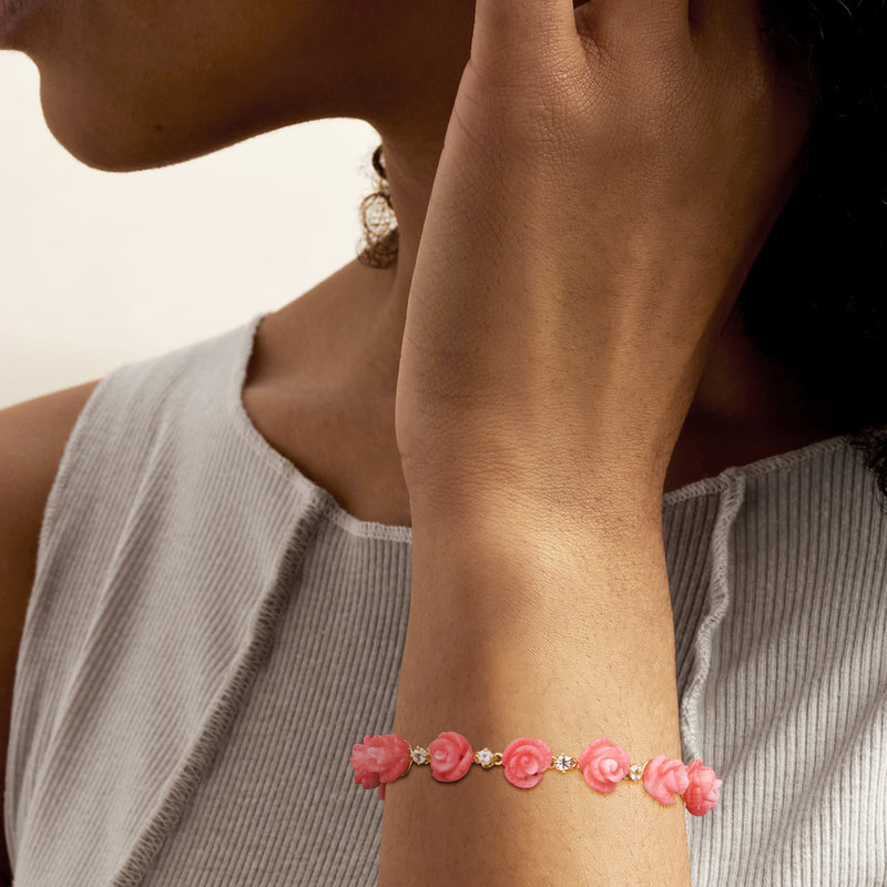 Pink rose coral bracelet with white stone links on wrist, gold chain