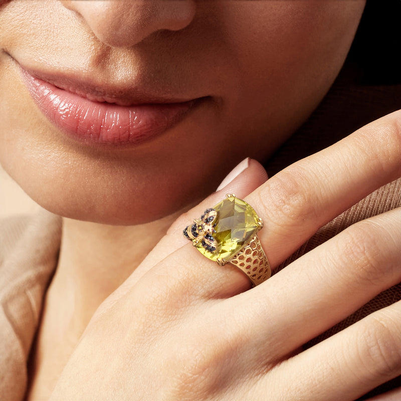 Lemon-yellow gemstone bee ring on hand, with gold lattice band and dark accents