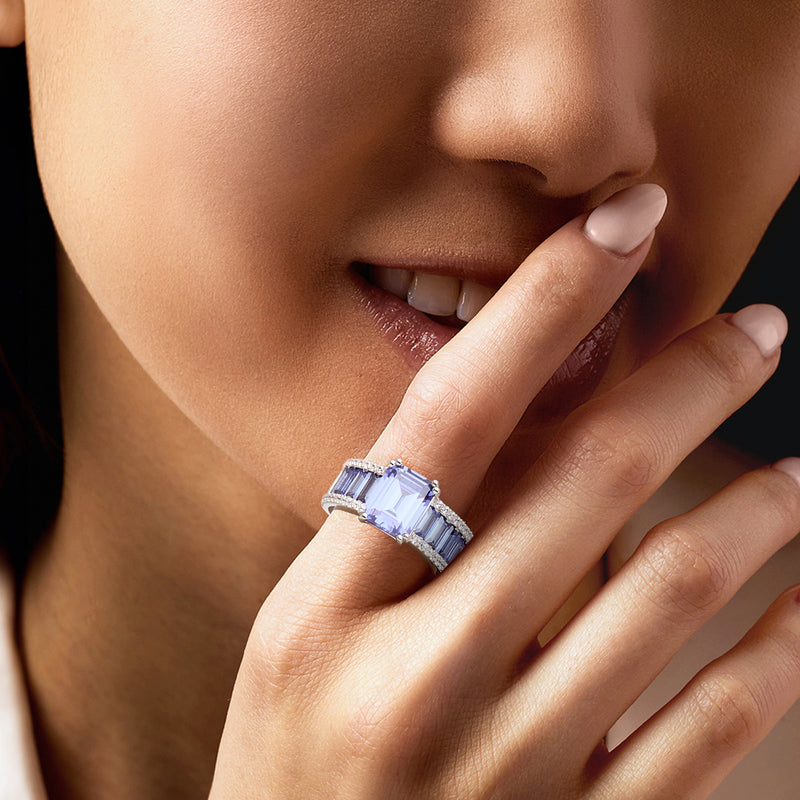 Sterling silver ring worn on finger with blue simulated stone and CZ side accents