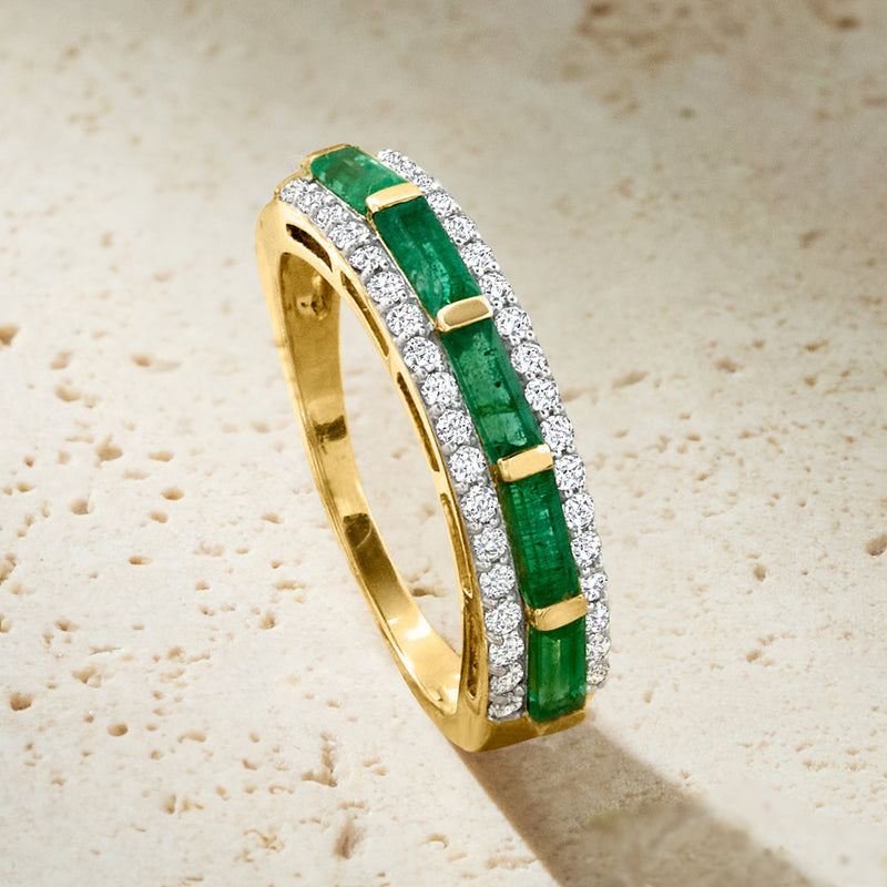 Gold ring close-up with emerald green center stones and white diamond pave border