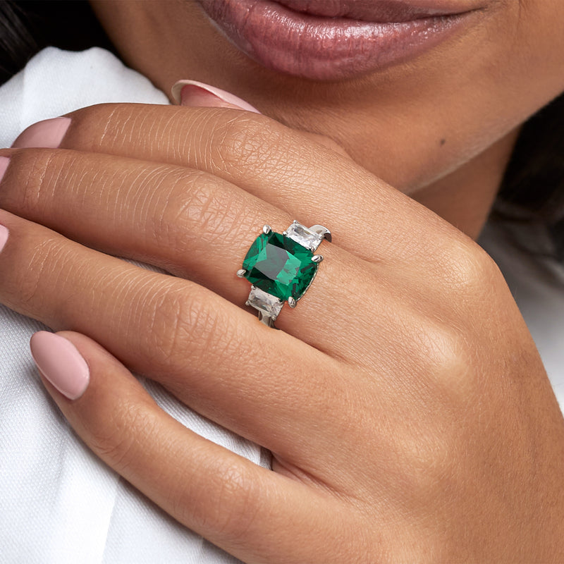 Sterling silver ring with green emerald-cut center and clear side CZ stones on hand