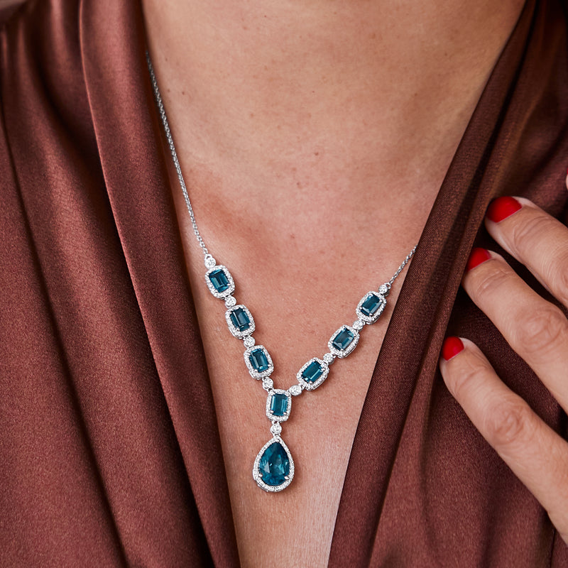 Sterling silver necklace with blue topaz link row and pear drop pendant, close-up