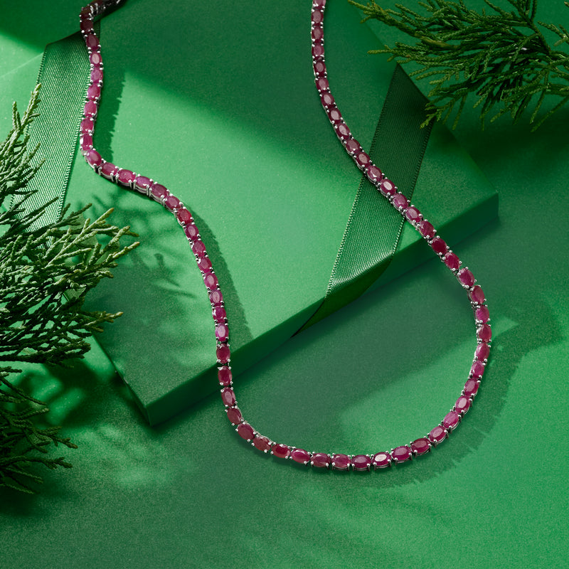 Ruby tennis necklace in sterling silver with pink oval stones on green gift-style background