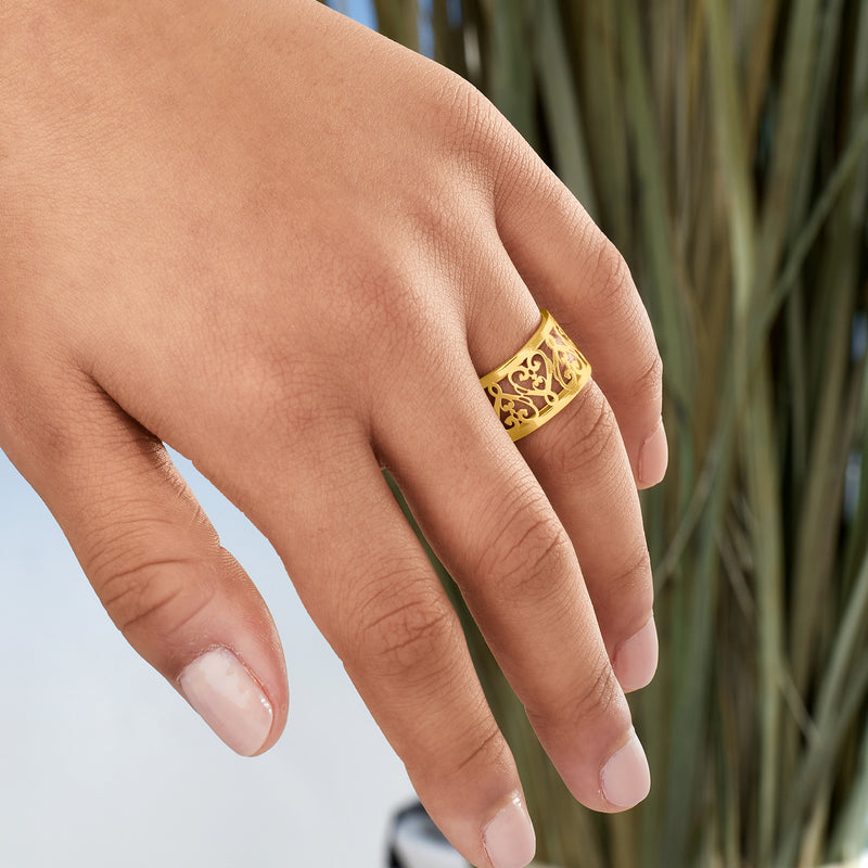 Yellow gold filigree heart ring on hand, showing ornate openwork band.