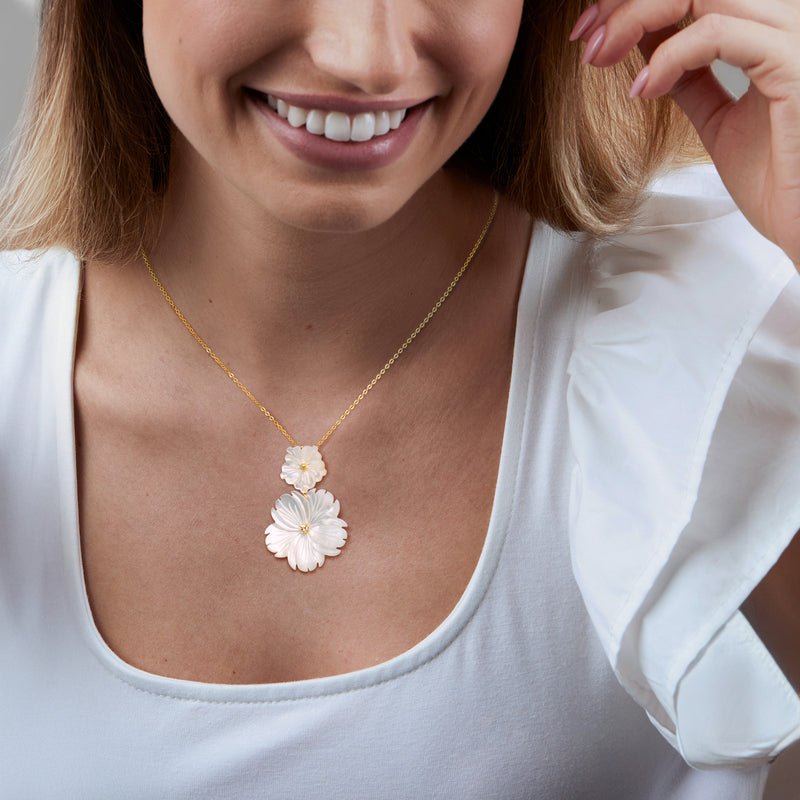 Gold necklace with two white flower pendants and sparkling center stones