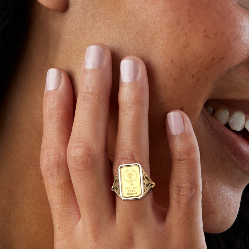 Yellow gold ingot ring worn on finger with fleur-de-lis top detail