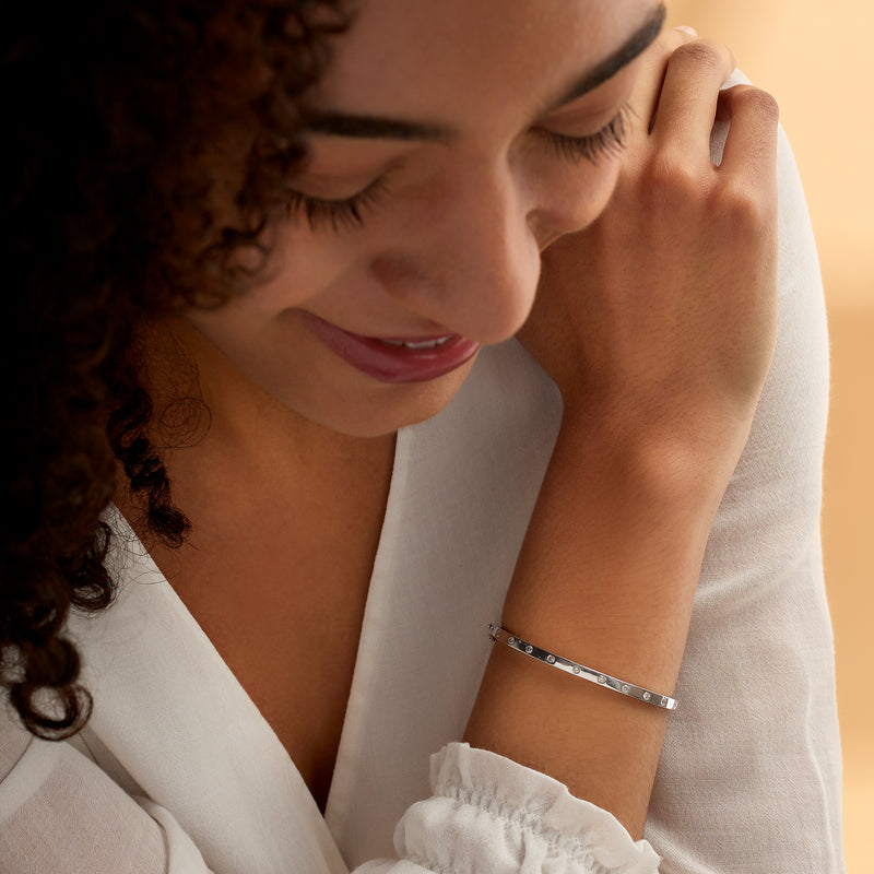 Sterling silver diamond bangle on wrist with small round stones across the band