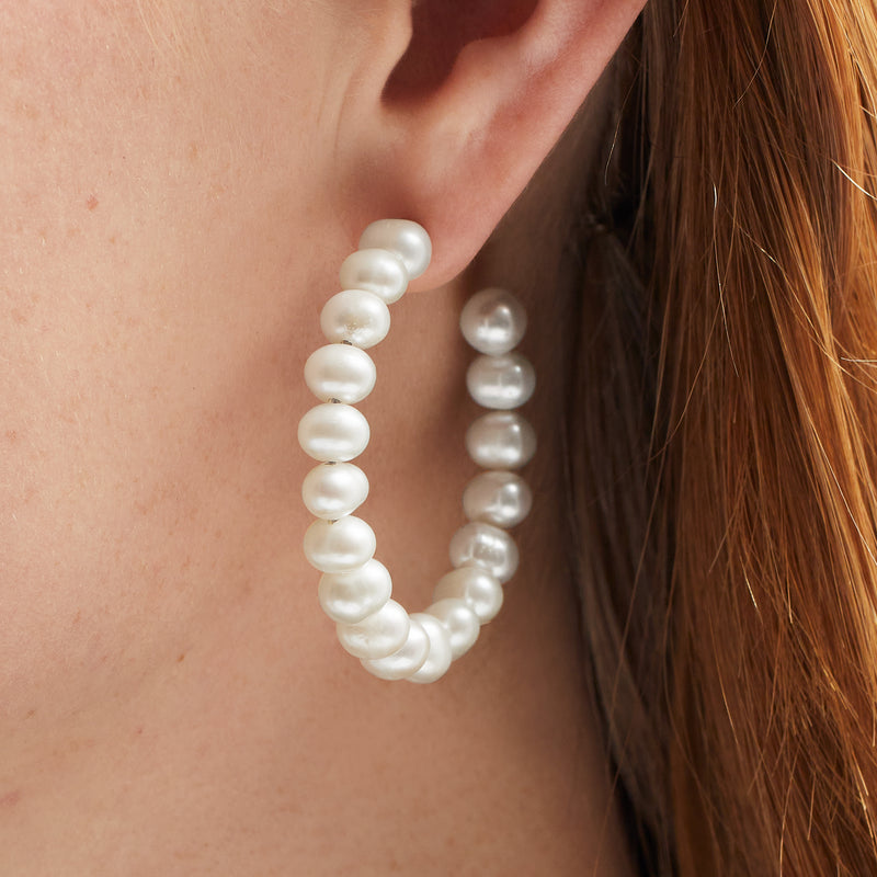 Cultured pearl hoop earrings shown on ear, round white pearls