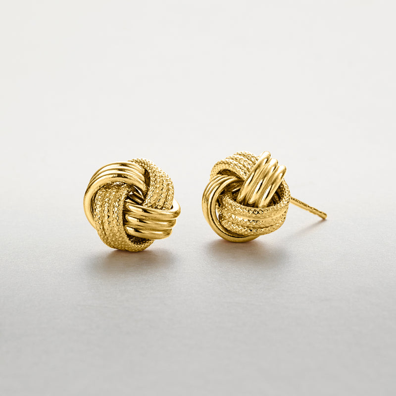 Gold love-knot stud earring with textured swirl design and visible backing post