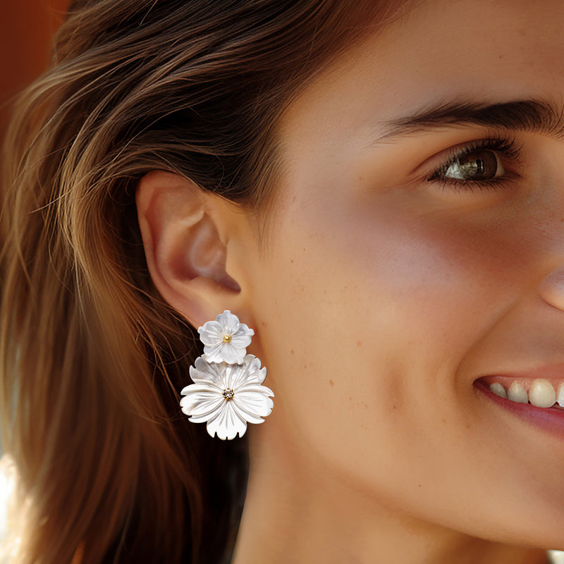 White mother-of-pearl flower drop earrings on model, gold posts with sparkling center stones