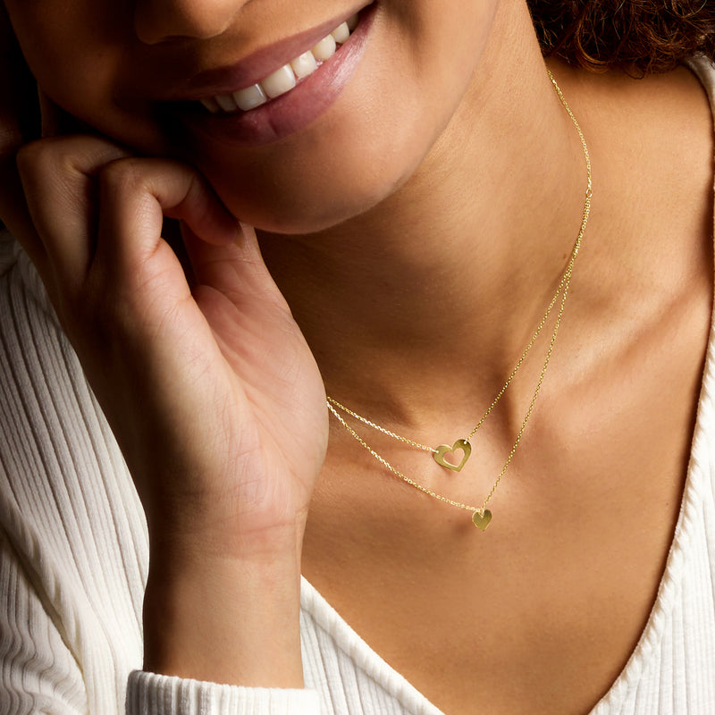 Yellow gold layered necklace with small and medium heart pendants on thin chains