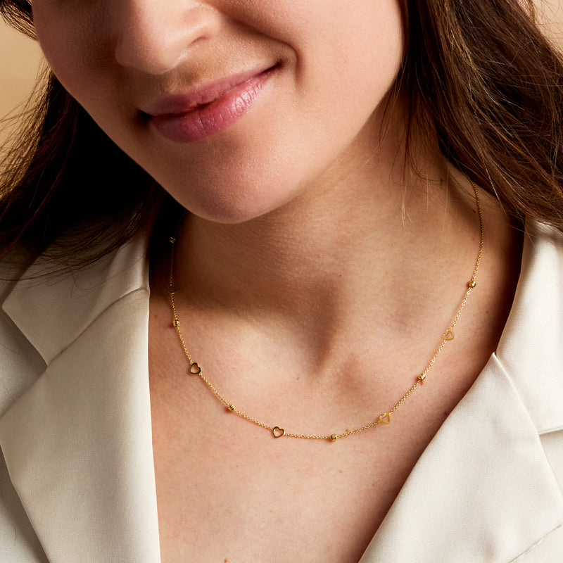 Close-up of 14kt yellow gold bead necklace with heart stations along chain