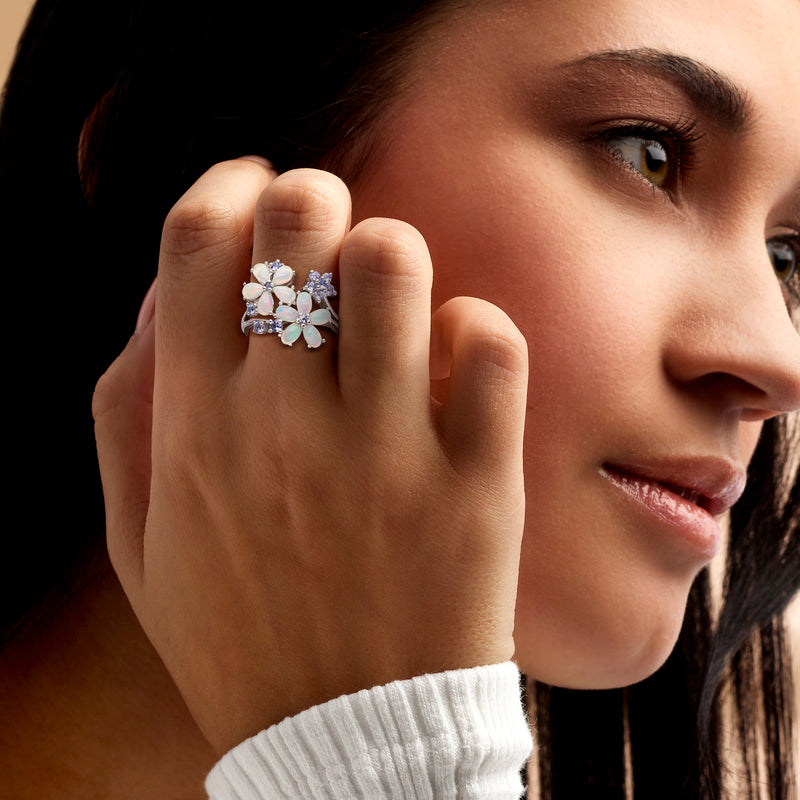 Opal and tanzanite flower ring in sterling silver worn on a hand, side view