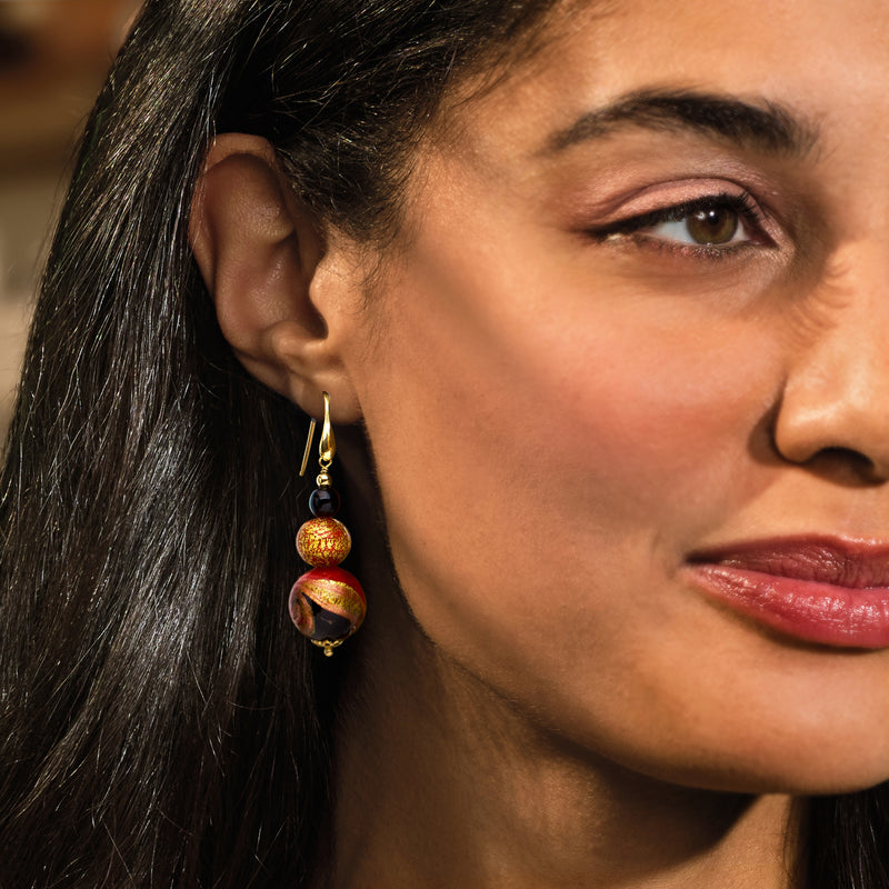Red, black, and gold glass bead drop earrings on gold earwires, side view