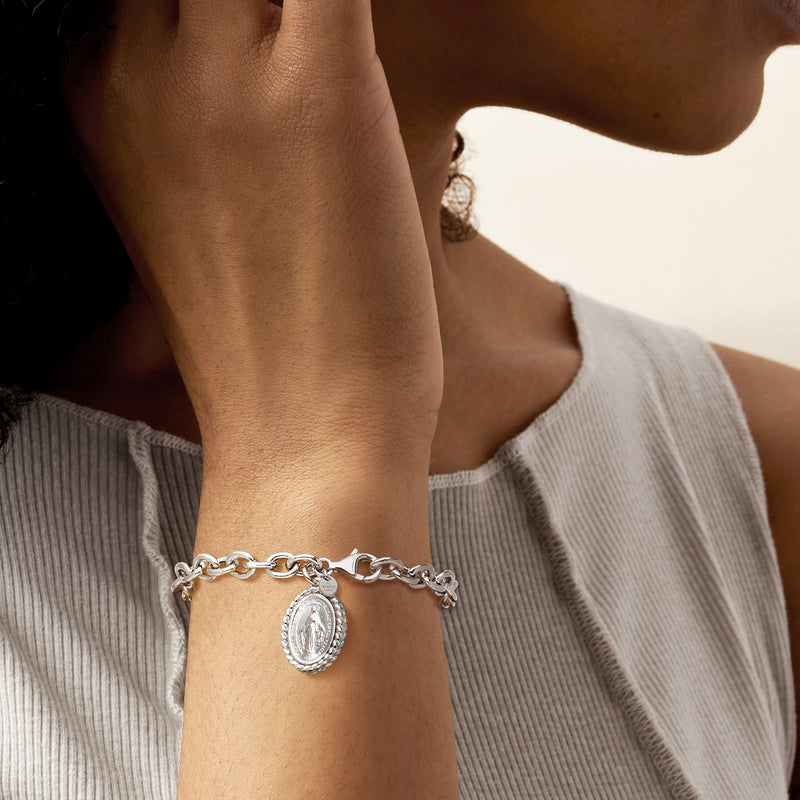 Sterling silver Miraculous Medal charm bracelet worn on wrist, oval pendant