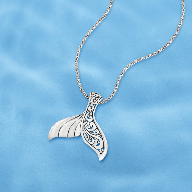 Sterling silver whale tail pendant necklace with sculpted tail and filigree, on chain.