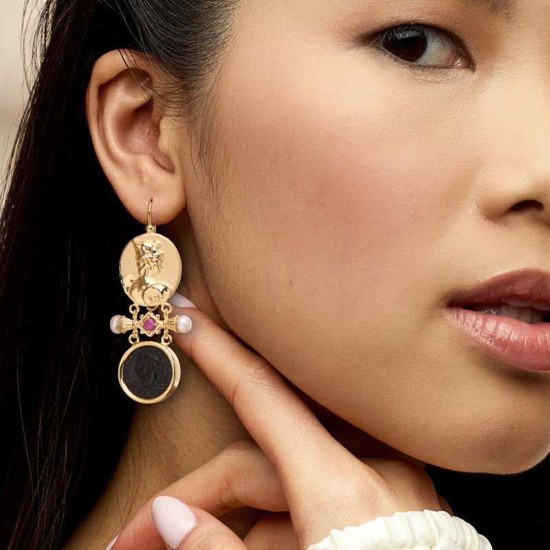 Gold drop earrings on model with purple ruby, white pearls, engraved oval and black onyx disc