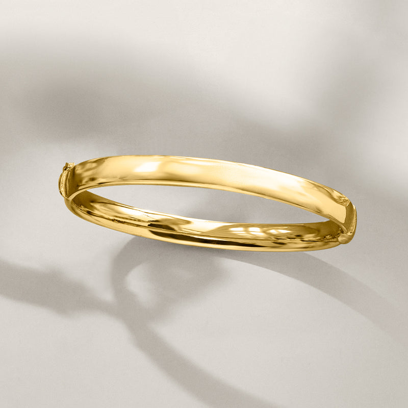 Oval gold-tone bangle bracelet in side view, smooth polished finish
